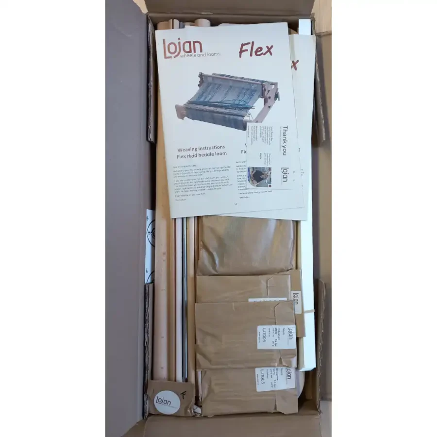Ο αργαλειός Lojan Flex στο κουτί Μια άποψη από πάνω ενός ανοιχτού κουτιού αποστολής που περιέχει τον αργαλειό Lojan Flex rigid heddle loom, με όλα τα εξαρτήματα τυλιγμένα και τακτοποιημένα, και το εγχειρίδιο οδηγιών στην κορυφή.