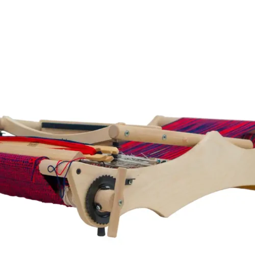 Ο επιτραπέζιος αργαλειός Louët Erica διπλωμένος επίπεδα για εύκολη αποθήκευση ή μεταφορά. Το ξύλινο πλαίσιο είναι χαμηλωμένο, ενώ το κόκκινο και μπλε υφασμένο ύφασμα και το στημόνι παραμένουν ανέπαφα και ασφαλή πάνω στον αργαλειό.