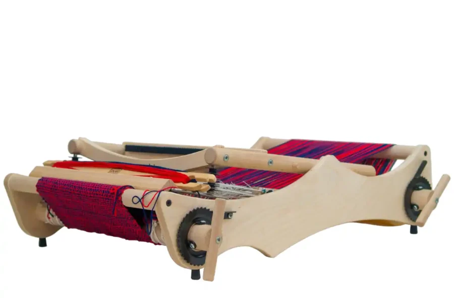 Louet Erica διπλωμένος Ο επιτραπέζιος αργαλειός Louët Erica διπλωμένος επίπεδα για εύκολη αποθήκευση ή μεταφορά. Το ξύλινο πλαίσιο είναι χαμηλωμένο, ενώ το κόκκινο και μπλε υφασμένο ύφασμα και το στημόνι παραμένουν ανέπαφα και ασφαλή πάνω στον αργαλειό.